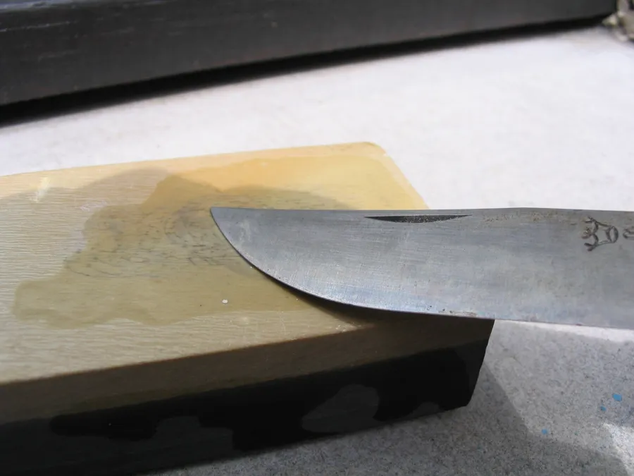 Kniv som slipes på slipestein med vann